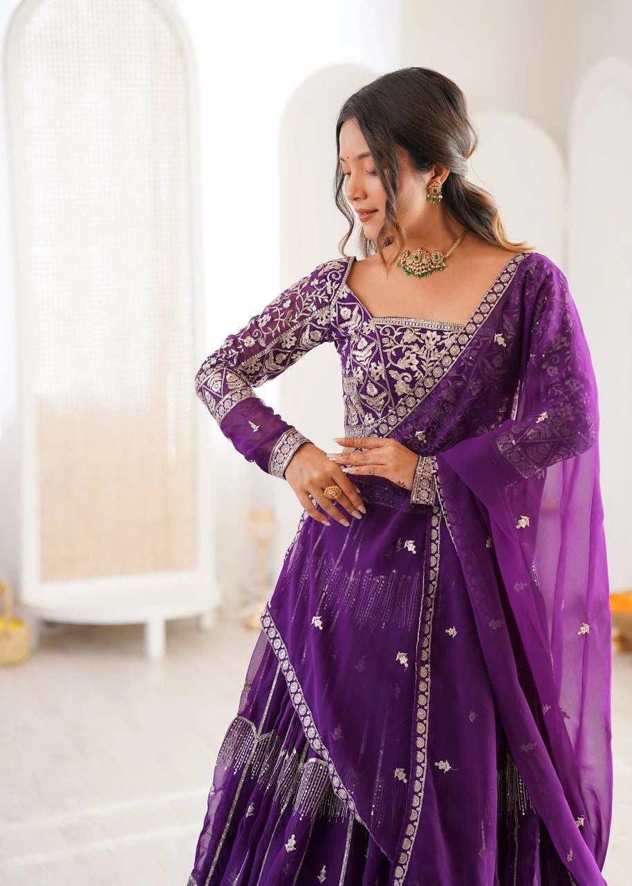 Woman wearing a purple traditional outfit with intricate designs indoors.